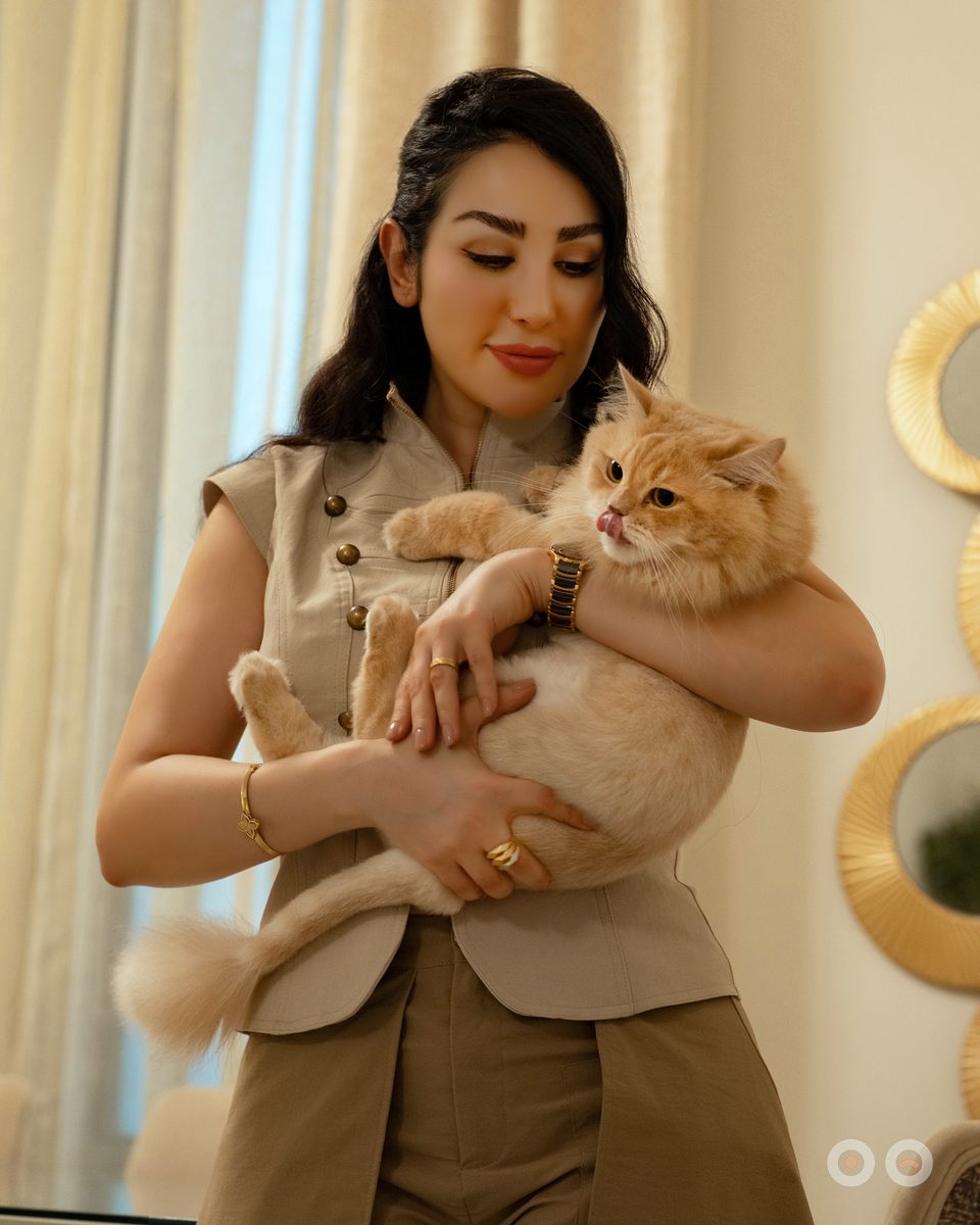 A ginger cat held close at home, on its own furniture, in its own light.