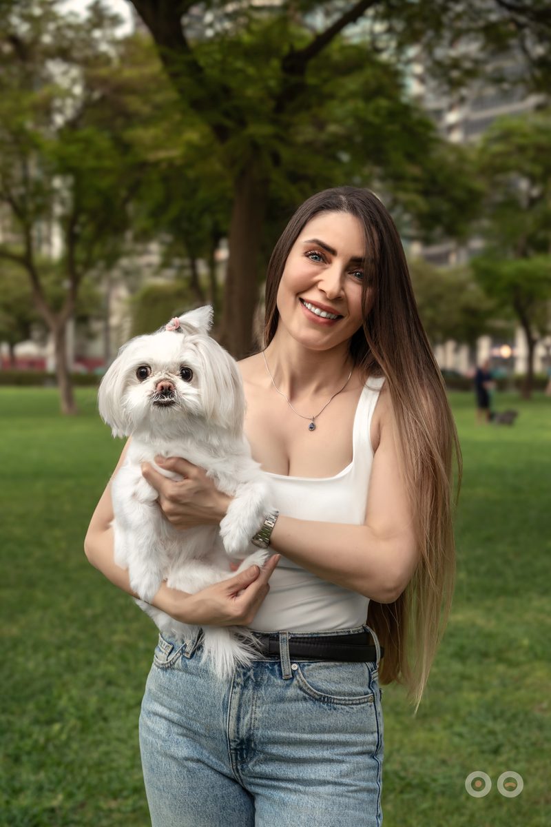 A woman holding her maltese in a Dubai park at the end of the day.
